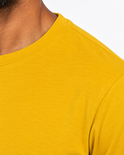 Detalhe lateral da gola e costura do ombro da camiseta amarela.